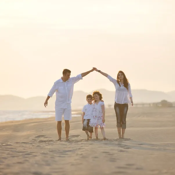 Familie am Strand bildet mit den Armen ein Dach
